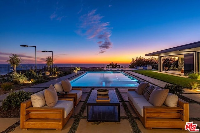 pool at dusk with an outdoor living space and a patio area