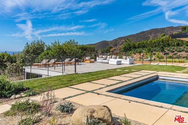 view of pool with outdoor lounge area, a mountain view, and a patio