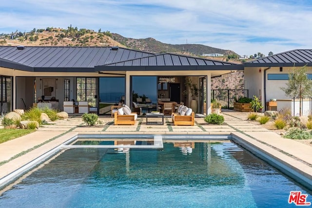 rear view of house featuring a swimming pool with hot tub, an outdoor living space, a mountain view, and a patio