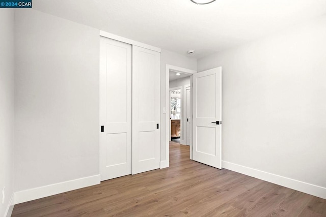 unfurnished bedroom with wood-type flooring and a closet