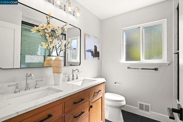 bathroom with toilet, vanity, and tile patterned floors