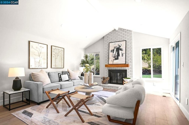 living room featuring a brick fireplace, vaulted ceiling, and light wood-type flooring