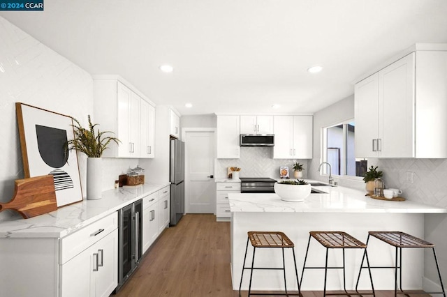 kitchen with appliances with stainless steel finishes, white cabinetry, a kitchen bar, and kitchen peninsula