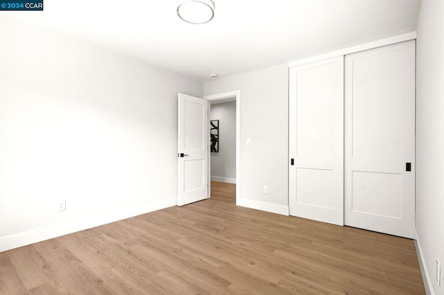 unfurnished bedroom with a closet and light hardwood / wood-style floors