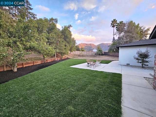 yard at dusk featuring a mountain view and a patio