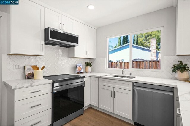 kitchen with appliances with stainless steel finishes, sink, dark hardwood / wood-style flooring, and white cabinetry