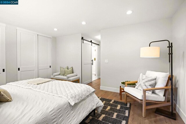 bedroom with a closet, a barn door, and hardwood / wood-style flooring