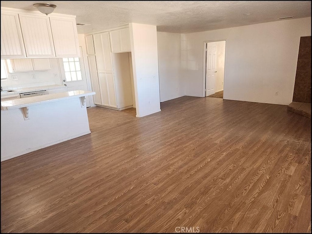 unfurnished living room with dark hardwood / wood-style floors and a textured ceiling