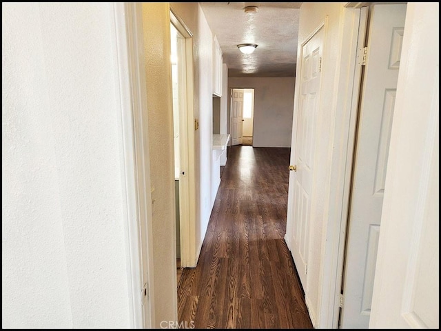 hallway featuring dark hardwood / wood-style flooring and a textured ceiling