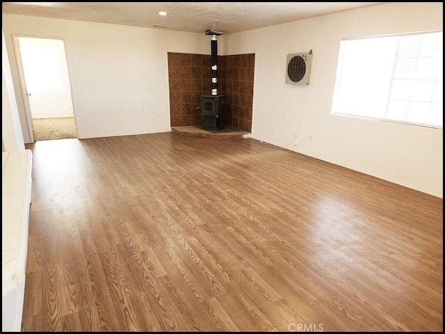 unfurnished living room with light wood-type flooring and a wood stove