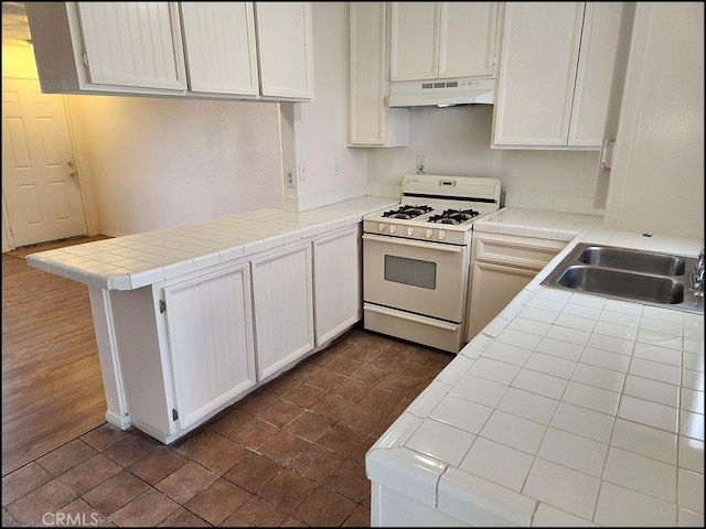 kitchen featuring tile counters, white cabinets, sink, and white gas range