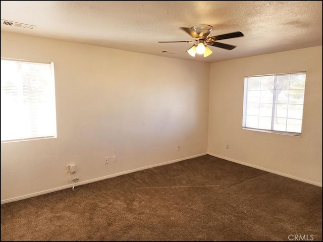 empty room with ceiling fan and dark colored carpet