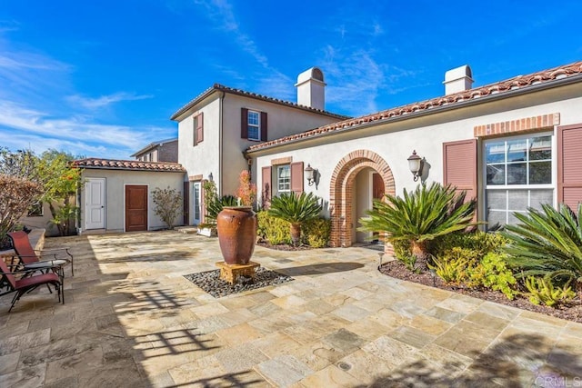 back of property featuring an outdoor structure and a patio