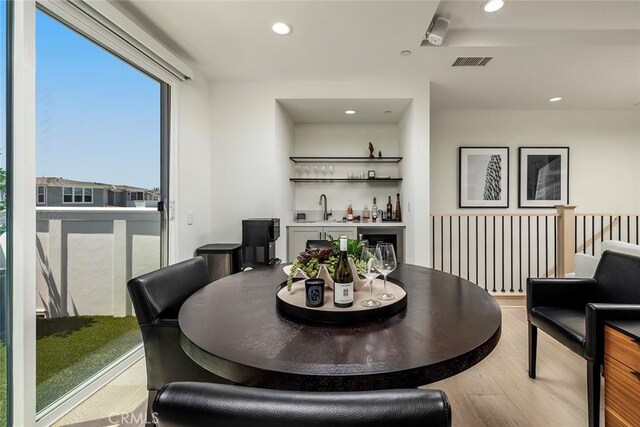 dining room with wet bar and hardwood / wood-style flooring