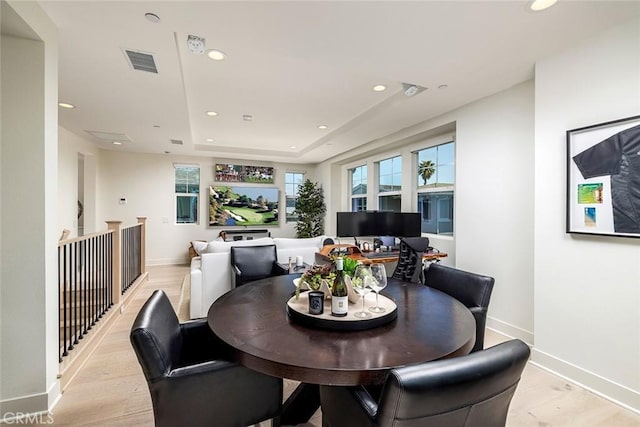 dining room featuring light wood-type flooring and a tray ceiling