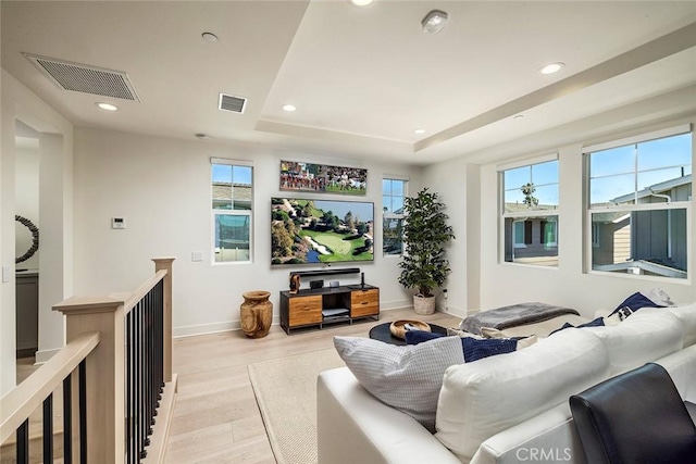 living room with a raised ceiling and light wood-type flooring