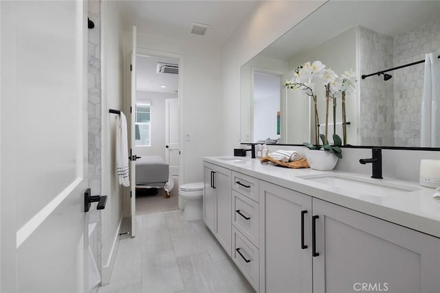 bathroom featuring toilet, tiled shower, and vanity