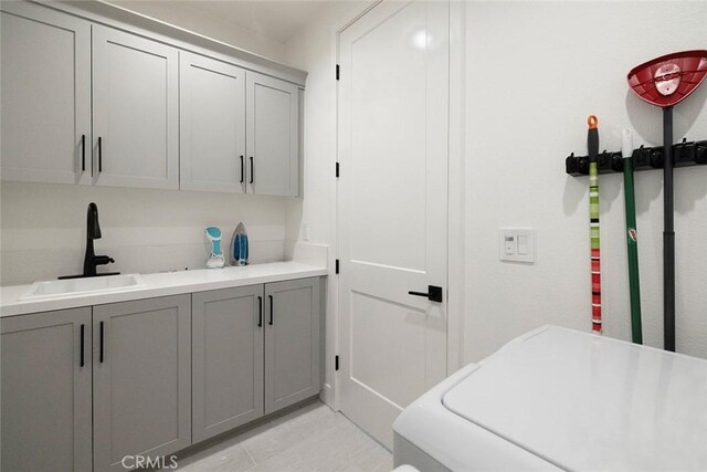 clothes washing area with washer / clothes dryer, sink, and cabinets