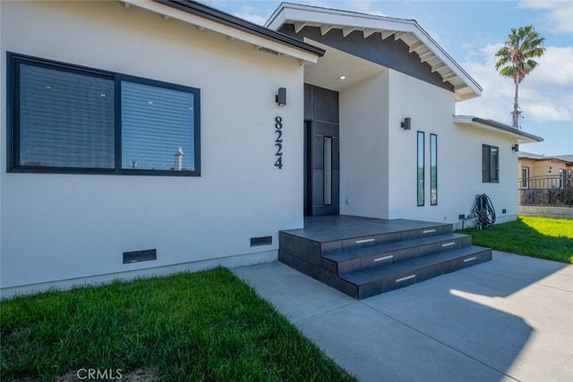 entrance to property with a patio area and a lawn