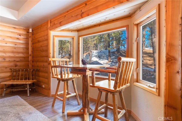 dining area with rustic walls, baseboards, and wood finished floors