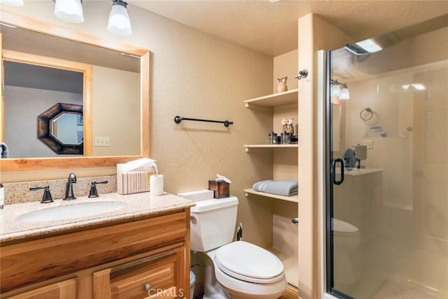 bathroom with toilet, a textured wall, a shower stall, and vanity