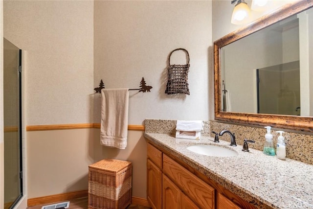 bathroom featuring visible vents, an enclosed shower, vanity, and baseboards