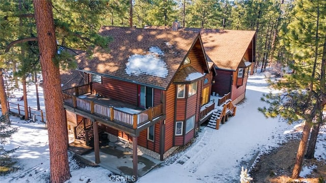 view of front facade featuring log veneer siding, a wooden deck, and roof with shingles