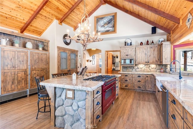 kitchen with arched walkways, a kitchen island, appliances with stainless steel finishes, brown cabinetry, and pendant lighting