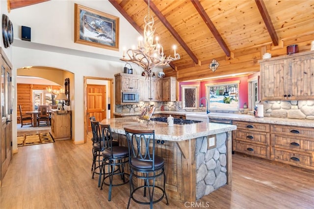 kitchen featuring stainless steel appliances, brown cabinets, light stone countertops, and a center island