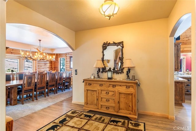 corridor featuring a healthy amount of sunlight, an inviting chandelier, and light hardwood / wood-style flooring