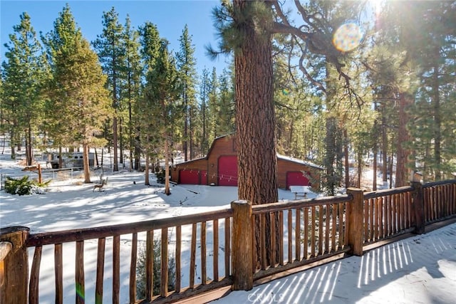 snow covered deck featuring a garage and a barn