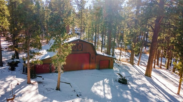 snow covered property with a detached garage, a barn, and an outdoor structure