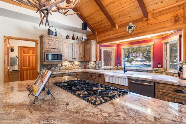 kitchen featuring sink, wood ceiling, appliances with stainless steel finishes, beam ceiling, and light stone counters