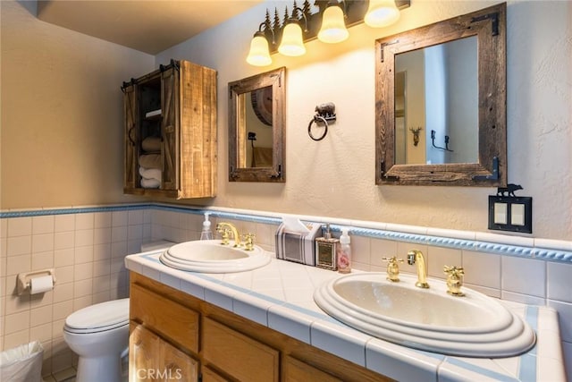 bathroom with vanity, tile walls, and toilet