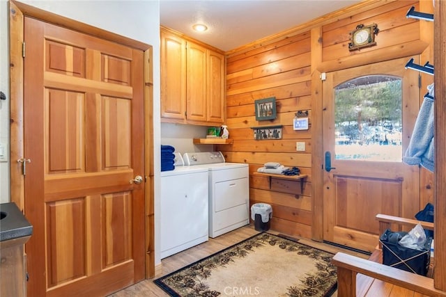 laundry area with cabinets, washer and dryer, light hardwood / wood-style floors, and wood walls