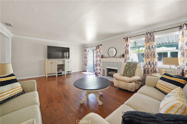 living room with a tiled fireplace, ornamental molding, and dark hardwood / wood-style floors