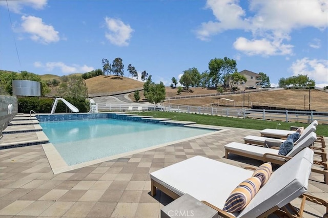 view of swimming pool with a diving board, a patio area, and a water slide