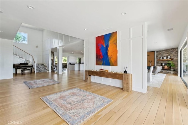 interior space with light wood-type flooring, a healthy amount of sunlight, and decorative columns