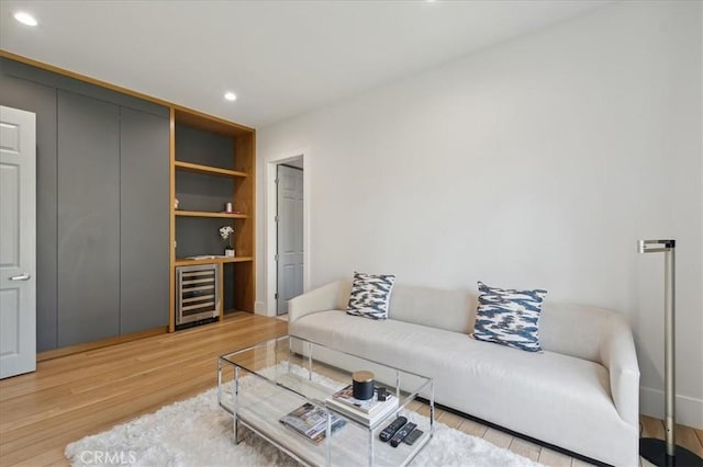 living room featuring wine cooler, built in shelves, and light wood-type flooring