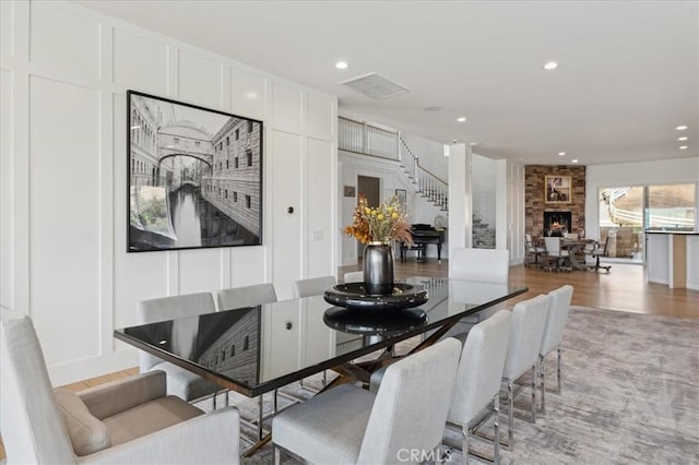 dining space with hardwood / wood-style flooring and a large fireplace