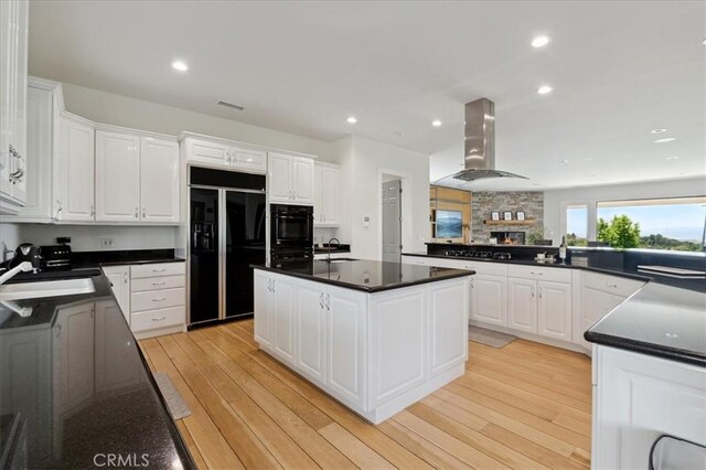 kitchen featuring exhaust hood, white cabinetry, sink, and black appliances