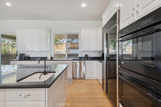 kitchen featuring double oven, dishwasher, white cabinetry, and light hardwood / wood-style flooring