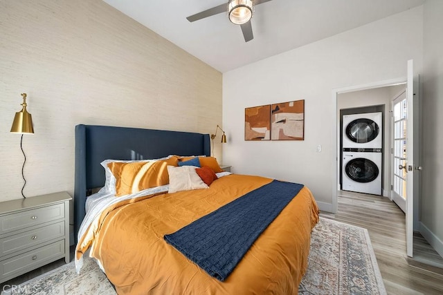 bedroom featuring ceiling fan, stacked washing maching and dryer, and light hardwood / wood-style floors