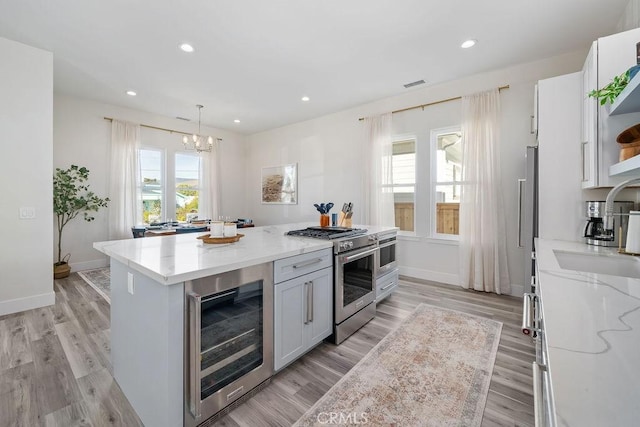 kitchen with pendant lighting, white cabinets, a center island, wine cooler, and high end stainless steel range oven