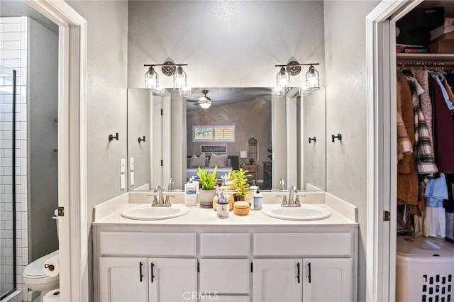 bathroom with toilet, vanity, ceiling fan, and an enclosed shower