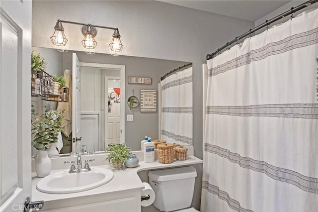 bathroom featuring toilet, vanity, and curtained shower