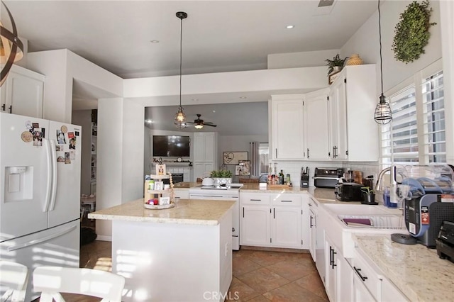 kitchen with ceiling fan, a center island, hanging light fixtures, white cabinets, and white fridge with ice dispenser