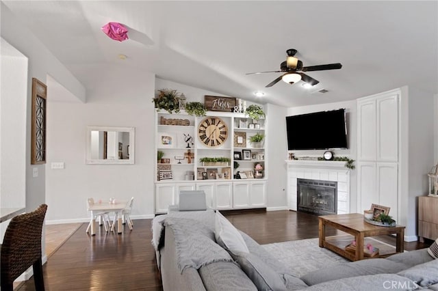 living room featuring dark wood-type flooring, lofted ceiling, a tile fireplace, and ceiling fan