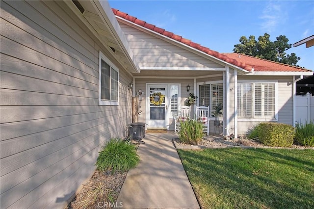 entrance to property with covered porch and a yard