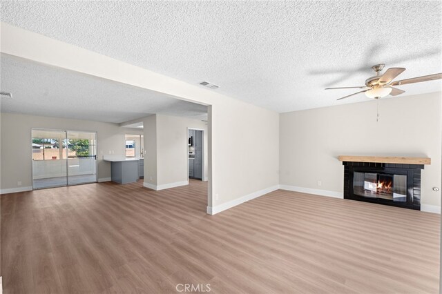 unfurnished living room with ceiling fan, a textured ceiling, and hardwood / wood-style flooring